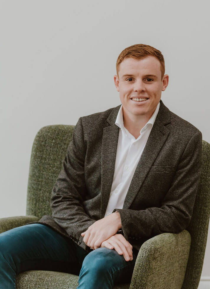 Photo of Jackson McMahon sitting in a contemporary green armchair.